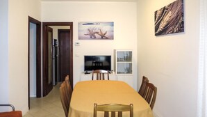 Un comedor con una mesa, sillas, un televisor y un armario.