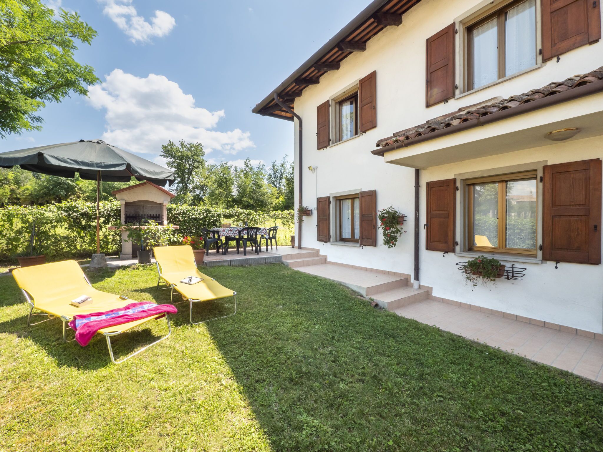 A two-story house with a patio, outdoor seating, and a well-maintained lawn.
