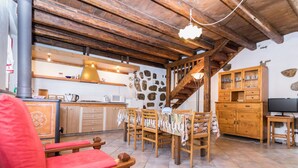 A rustic interior with a wooden dining table, chairs, a sofa, a kitchen area, and a staircase. - Al Rustico by Interhome (San Giovanni al Natisone)