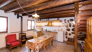 A rustic kitchen with wooden beams, a dining table, and a red chair. - Al Rustico by Interhome (San Giovanni al Natisone)