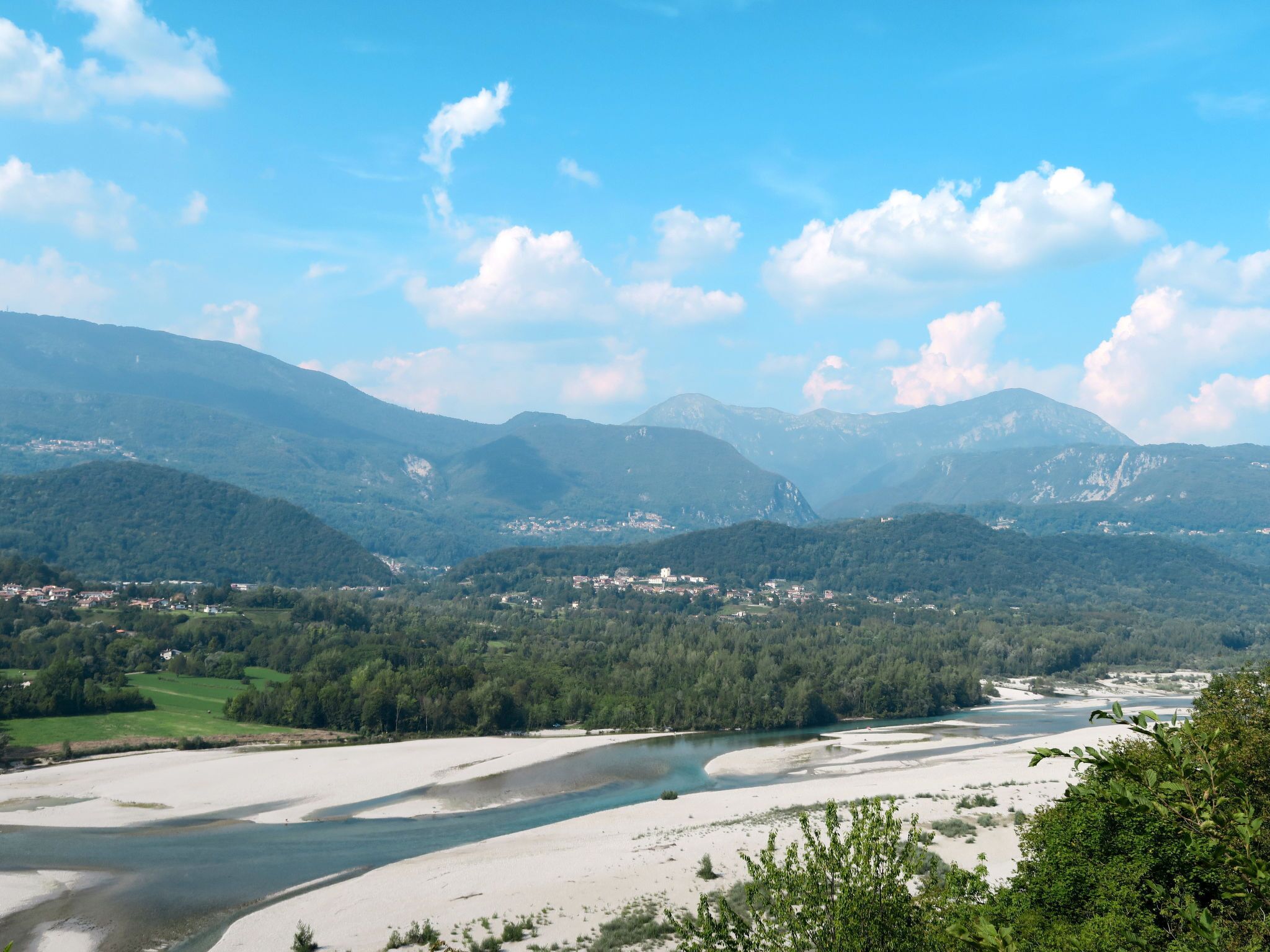 A river flowing through a valley with mountains in the background.