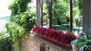 A stone wall with a planter of red flowers, a metal gate, and a statue of a rabbit.