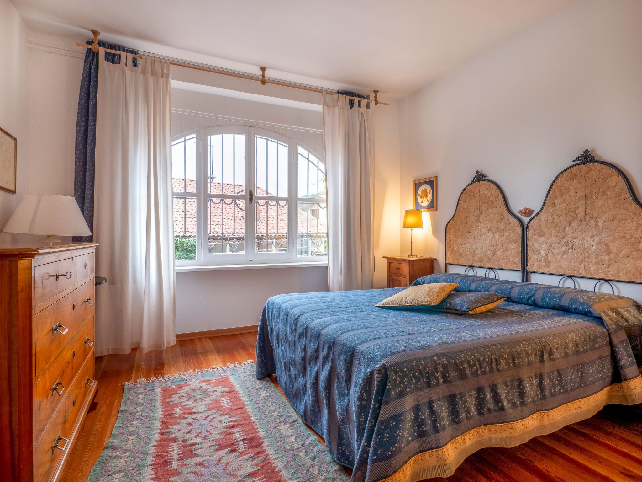Ein Schlafzimmer mit einem Bett, einer Holzkommode und einem Fenster mit Vorhängen.