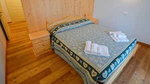 Un dormitorio con cabecera de madera, una cama con edredón estampado y una mesita de noche.