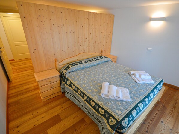 A bedroom with a wooden headboard, a bed with a patterned bedspread, and a nightstand.