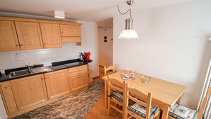 Una cocina compacta con armarios de madera, encimera de granito, mesa de comedor con sillas e iluminación colgante.