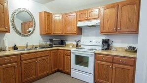 A kitchen with wooden cabinets, a white stove, a microwave, and a coffee maker.