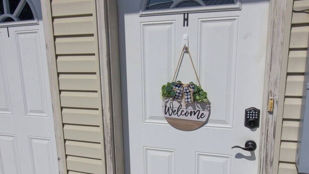 A white door with a 'Welcome' sign and a small plant hanging above it.