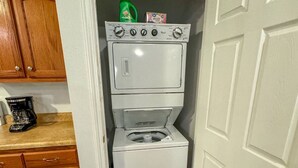 A compact laundry room with a washer and dryer, wooden cabinets, and a coffee maker on the countertop.