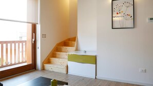 A modern kitchen with wooden stairs, a dining table, and a framed artwork on the wall.