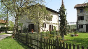 A rustic stone building with a garden, a wooden fence, and a clear sky. - Casa del Ligustro by Interhome (Strassoldo)