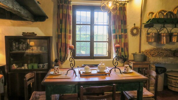 A dining area with a wooden table, chairs, a window with curtains, and a chandelier. - Casa del Ligustro by Interhome (Strassoldo)