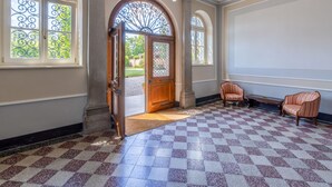 Una habitación amplia con piso de cuadros, un gran arco y dos sillones tapizados.