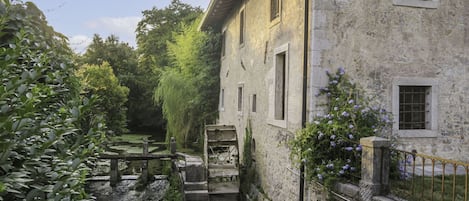 A stone building with a narrow waterway and lush greenery.