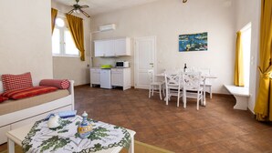 A compact living space with a sofa, dining table, kitchen area, and a ceiling fan. - Winery Villa Vitas Dépendance (App.1) by Interhome (Strassoldo)