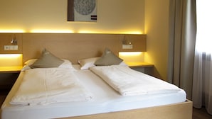 A double bed with two pillows, a wooden headboard, bedside lamps, and a wall-mounted artwork. - Schöneck by Interhome (Postal)