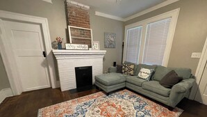Un salon avec une cheminée, un canapé d’angle et un tapis à motifs.