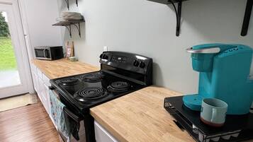 A kitchen with a black stove, wooden countertop, and a coffee maker on a tray.