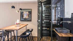 Ett modernt kök med ett vinkylskåp, ett träbord och svarta barstolar.