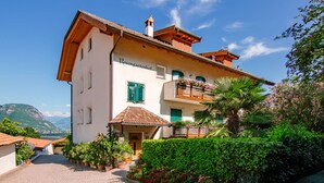 A two-story building with a balcony, a small porch, and a garden with potted plants and flowers. - Rosengartenhof by Interhome (Andriano)