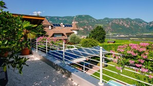 Zona residencial con una casa que tiene paneles solares, rodeada de vegetación y montañas.