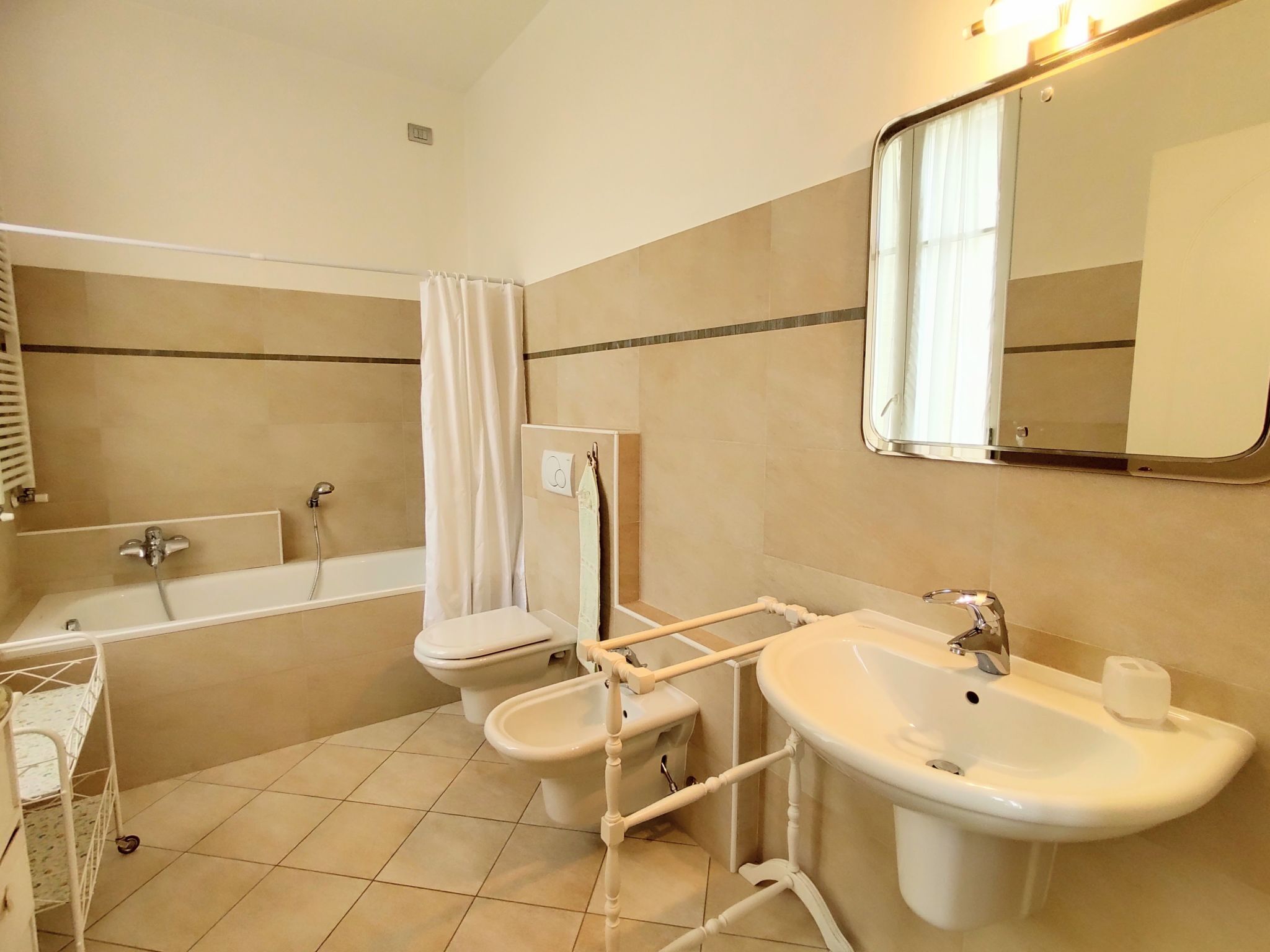 A bathroom with a bathtub, two sinks, a toilet, and a shower curtain.