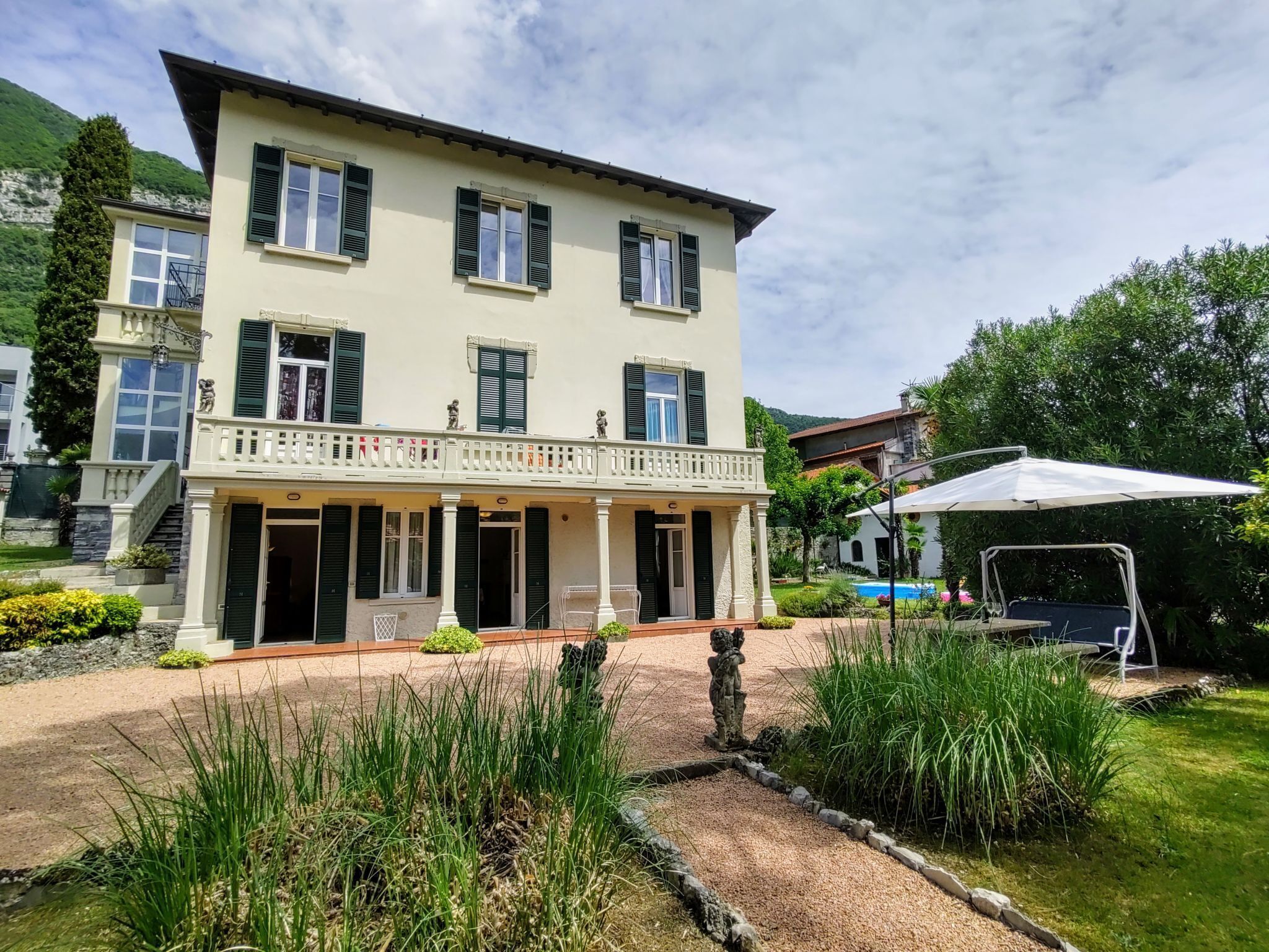 Un immeuble de deux étages doté d’un balcon, d’une piscine et d’un jardin.