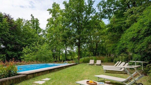 A backyard with a swimming pool, two lounge chairs, a picnic table, and a garden area.