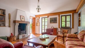 A cozy living room with a fireplace, leather chairs, a wooden coffee table, and a patterned sofa.