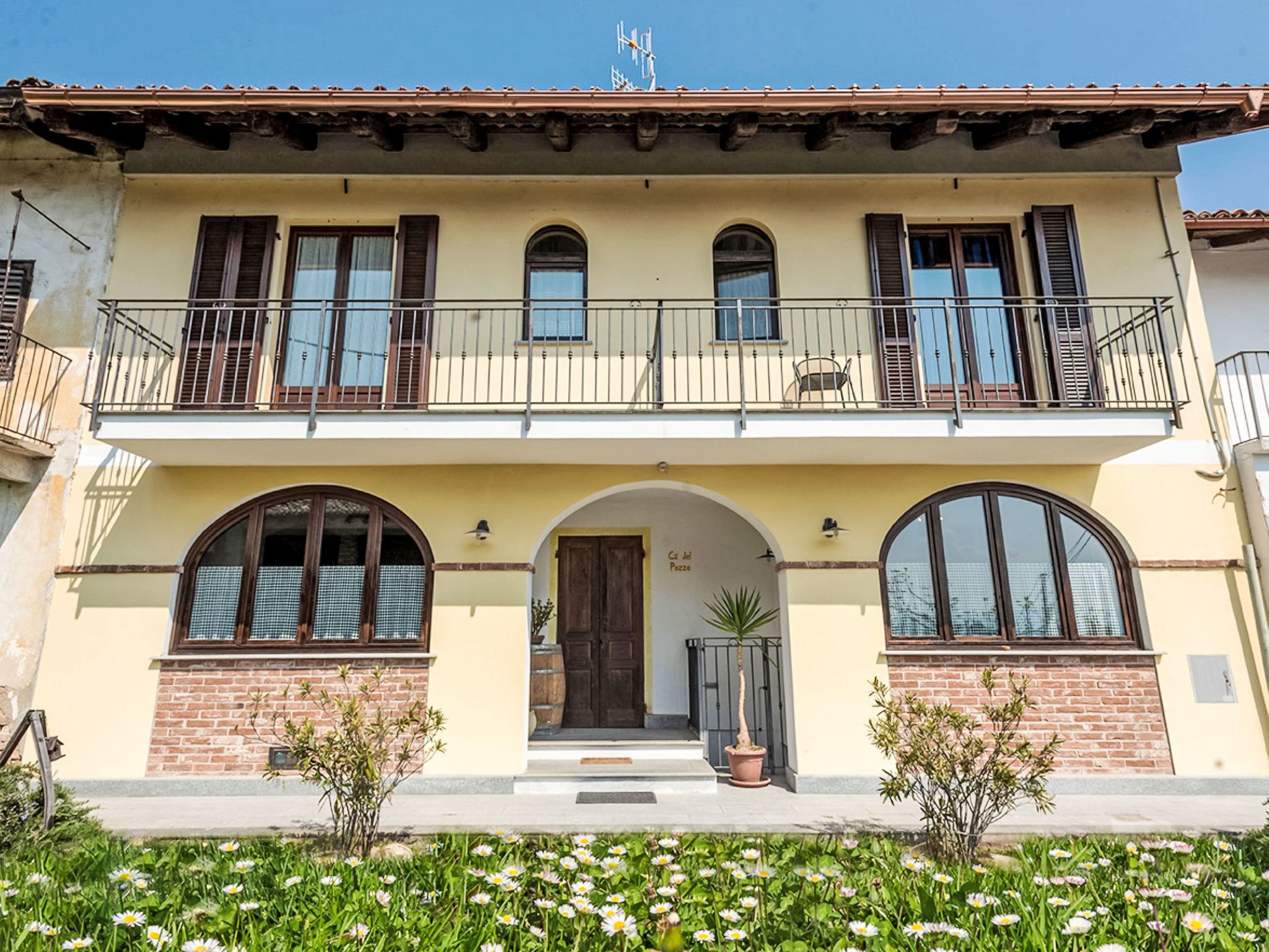 A two-story building with a balcony, arched windows, and a brick facade.