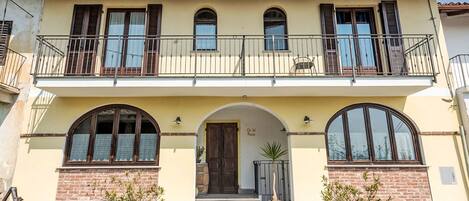 A two-story building with a balcony, arched windows, and a brick facade.