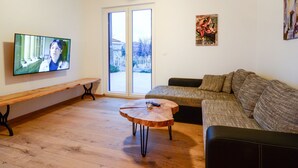 Een woonkamer met een televisie, een houten salontafel, een bank en een lange zitbank.