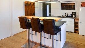 Een moderne keuken met een bar, witte kasten en een houten accentmuur.