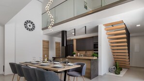 A modern dining area with a wooden table set for six, grey upholstered chairs, and a black clock on the wall. - Pinnidae by Interhome (Rab/Lopar)