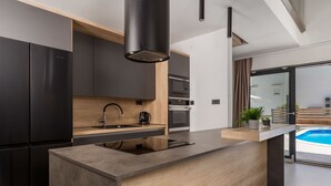 A modern kitchen with a built-in island, stainless steel appliances, and a view of a swimming pool. - Pinnidae by Interhome (Rab/Lopar)