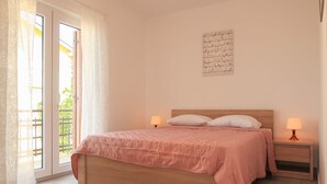Ein Schlafzimmer mit einem hölzernen Bett, zwei Nachttischlampen, einem Fenster mit Vorhängen und einem Wandbild.