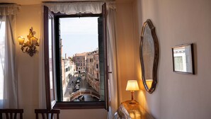 A room with a view of a canal and buildings, a lamp on a table, and a mirror on the wall. - Casa Allegra by Ca-sa Check (Venice)