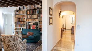 A cozy living room with a bookshelf, a floral armchair, and a teal sofa. - Casa Allegra by Ca-sa Check (Venice)