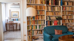 A cozy living room with a teal sofa, a wooden coffee table, and a bookshelf filled with books. - Casa Allegra by Ca-sa Check (Venice)