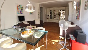 A modern living room with a glass dining table, a sofa, a TV, and a bookshelf. - Apartment in the Heart of Venice by Ca-sa Check (Venice)