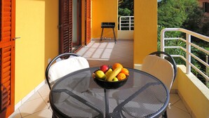 Un balcon avec une table ronde, des chaises et un saladier rempli de fruits.