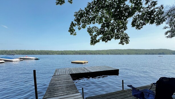 A wooden dock extending into a calm lake with boats docked nearby. - Pleasant Mountain Escape 5BR Condo with Moose Pond Access (Bridgton)