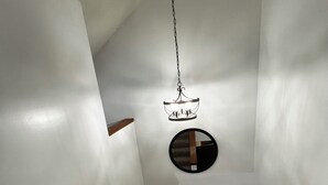 A narrow stairway with a wooden table at the bottom and a hanging light fixture above. - Pleasant Mountain Escape 5BR Condo with Moose Pond Access (Bridgton)