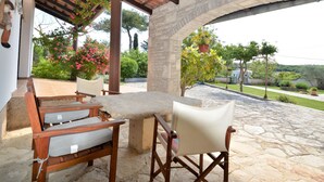 An outdoor patio with stone flooring, a wooden table, and two chairs.
