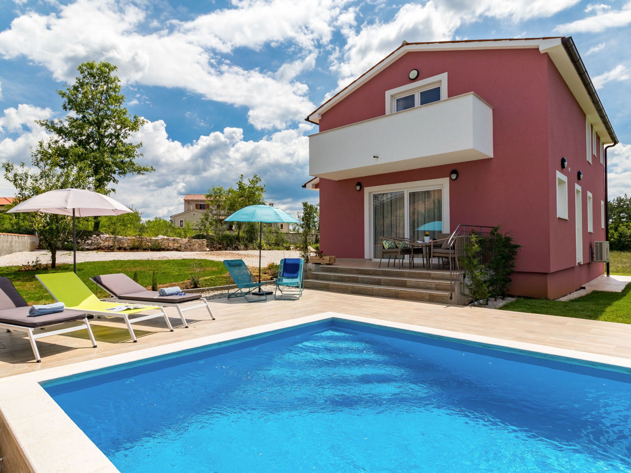 A poolside area with a pool, lounge chairs, and umbrellas.