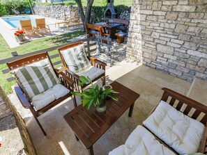 A patio with outdoor furniture, a stone wall, and a pool.