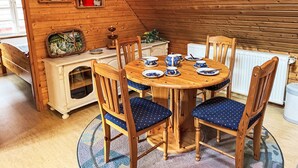 A cozy wooden dining area with a round table set for four, surrounded by matching chairs with blue cushions. - Brigitte by Interhome (Katzow)