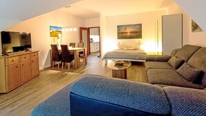 Un espacio habitable compacto con comedor, sofá, televisor y un cuadro en la pared.