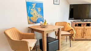 Een gezellige woonkamer met een houten tafel, twee stoelen, een televisie en een houten kast.