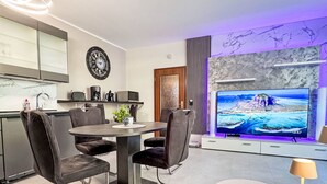 Un salon moderne comprenant un coin repas, un téléviseur à écran plat et un mur en marbre.
